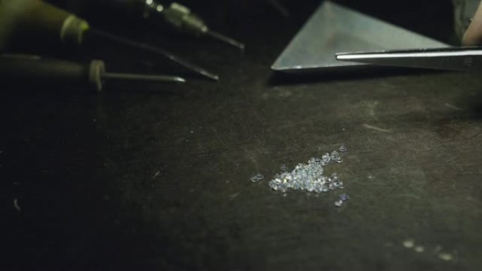 一个金匠的长凳上有一些钻石的特写，背景是一些工具。