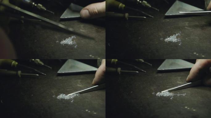 一个金匠的长凳上有一些钻石的特写，背景是一些工具。