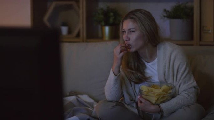 女人在家里吃薯条和看电影