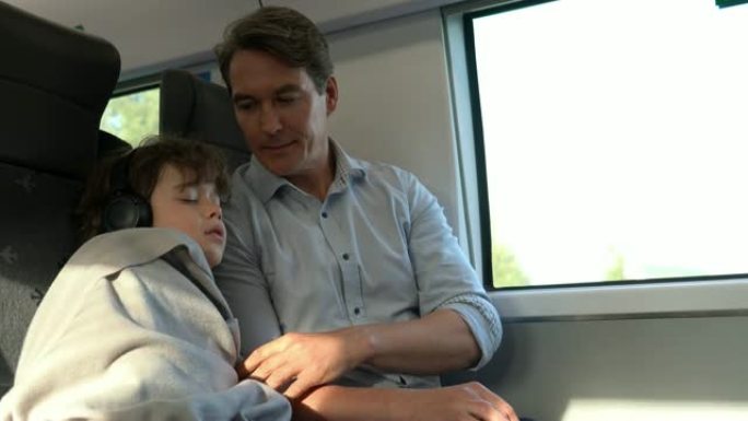 慈爱的父亲白天在火车上通勤时用毯子盖住儿子