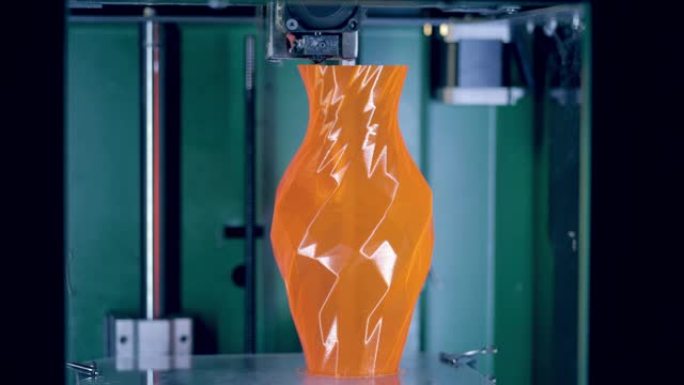 在3D打印机上打印的橙色花瓶。
