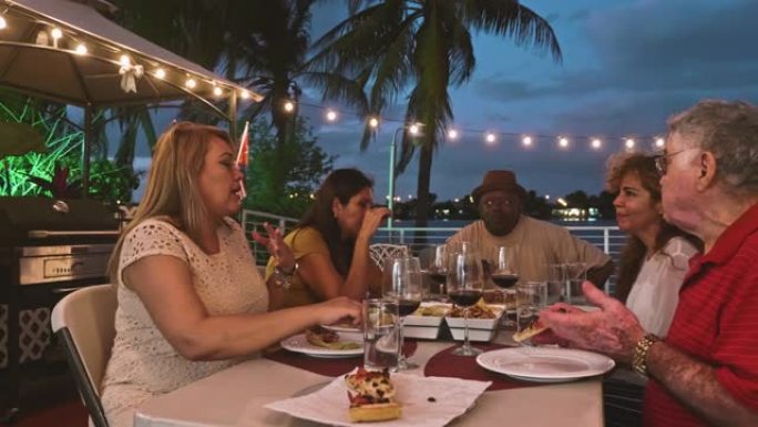 西班牙裔和非裔美国人朋友在露台户外用餐