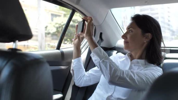 女商人在出租车上用智能手机拍照
