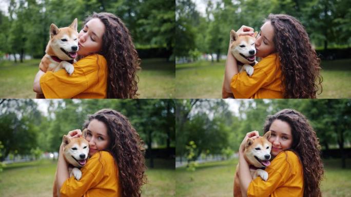 夏天在公园里抱着狗亲吻和拥抱宠物的善良女士的肖像