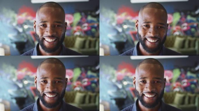 千禧一代黑人男子在工作场所的壁画前对镜头微笑，头部射击