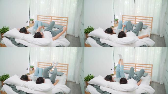 年轻的亚洲夫妇在床上一起玩耍，而早上在床上醒来。