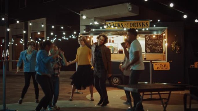 一群朋友正在街头食品汉堡咖啡馆外面举行聚会。他们跳舞并转向时尚音乐。今天是在一个现代凉爽的街区的夜晚