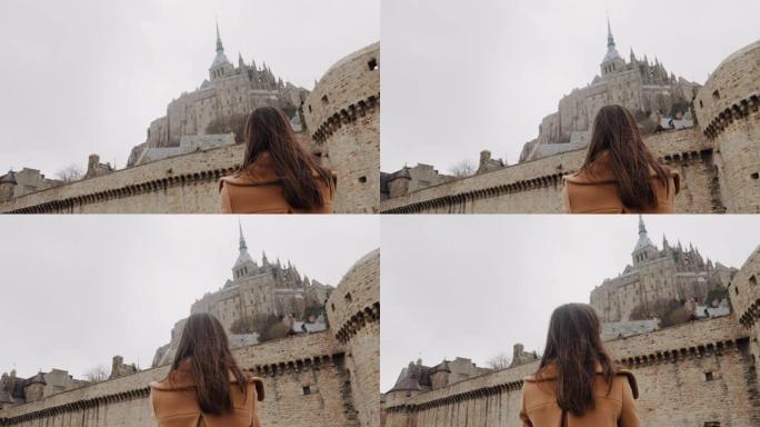低角度后视，美丽快乐的旅游女人被令人难以置信的圣米歇尔城堡景观慢动作惊呆了。