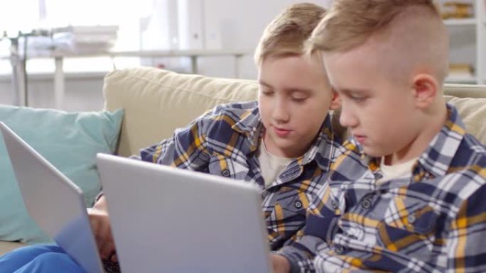 10岁的高加索双胞胎在笔记本电脑上做作业