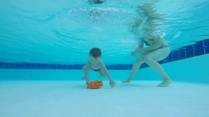 一个在游泳池里学习潜水的婴儿。蹒跚学步的孩子在水下游泳。