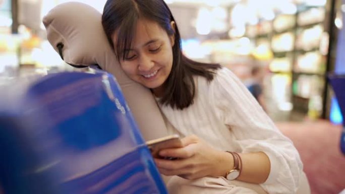 在aiport等待飞机飞行时，使用智能手机或手机倾斜亚洲女性