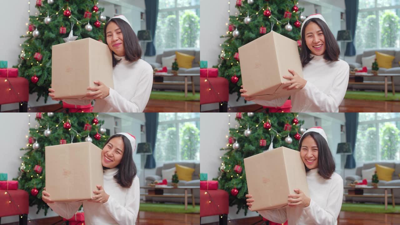 亚洲女性庆祝圣诞节。女性青少年穿毛衣和圣诞帽放松快乐拿着礼物在圣诞树附近微笑在家客厅一起享受圣诞寒假