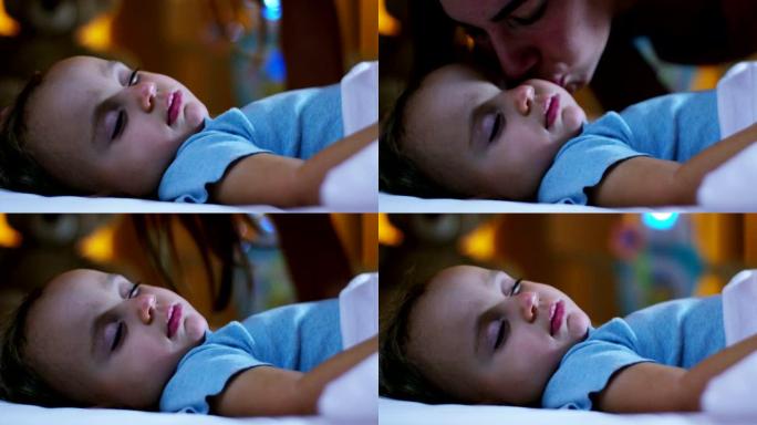 漂亮的妈妈在睡觉前给她的宝宝一个前吻，用羊毛材料上的粉色和蓝色毯子非常甜蜜地覆盖她，温暖