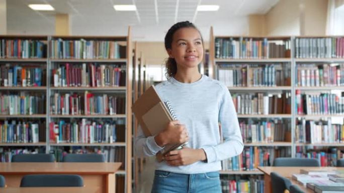 开朗的十几岁的女孩在高中图书馆微笑着走路