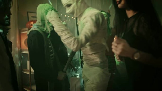 万圣节服装派对: 一群怪物在装饰有迪斯科球灯的房间里跳舞。脑死亡僵尸，嗜血德古拉，绷带木乃伊美丽的女