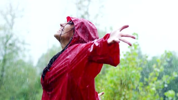 一个快乐的女人在雨中微笑，女人沉浸在快乐自由的雨中慢动作下的舞蹈中。