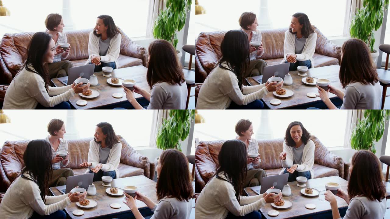 四名年轻的成年女性在咖啡馆里喝咖啡和蛋糕聊天