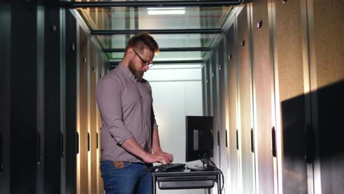 男性程序员与数据中心的计算机检查设备一起工作。