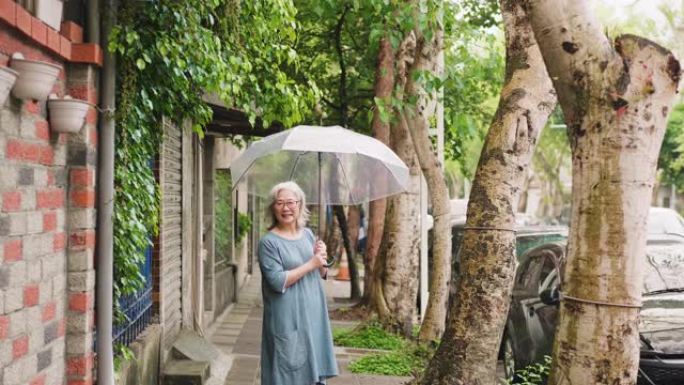 城市雨天带伞的快乐高级妇女