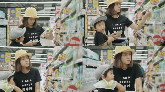 年轻的母亲和她的男孩在超市使用智能手机。