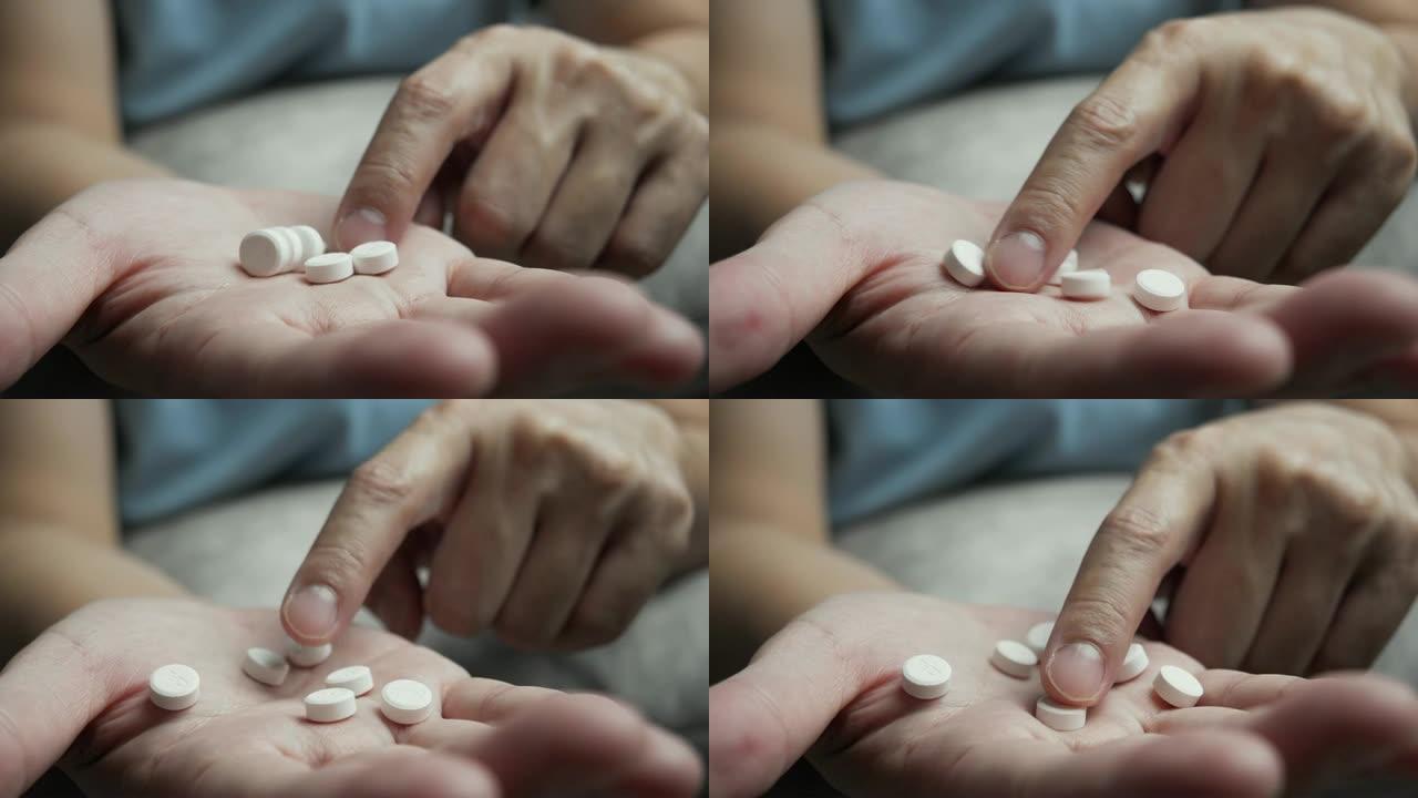 一名亚裔男子手上数着白色药丸的4k镜头。医学概念