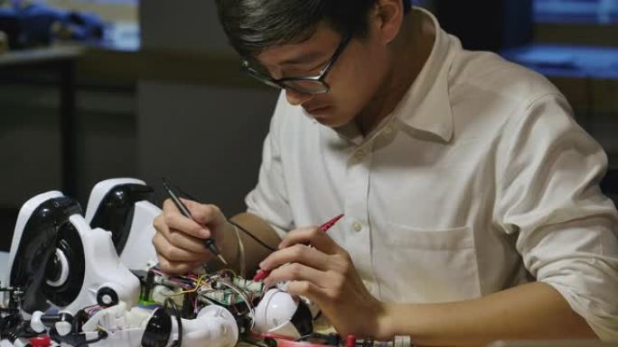 年轻的亚洲电子开发工程师在夜间在计算机科学研究实验室中建造，测试，固定机器人技术。有技术或创新概念的