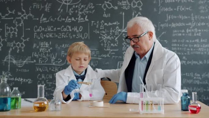 小男孩在学校进行化学测试，而老师则帮助解释