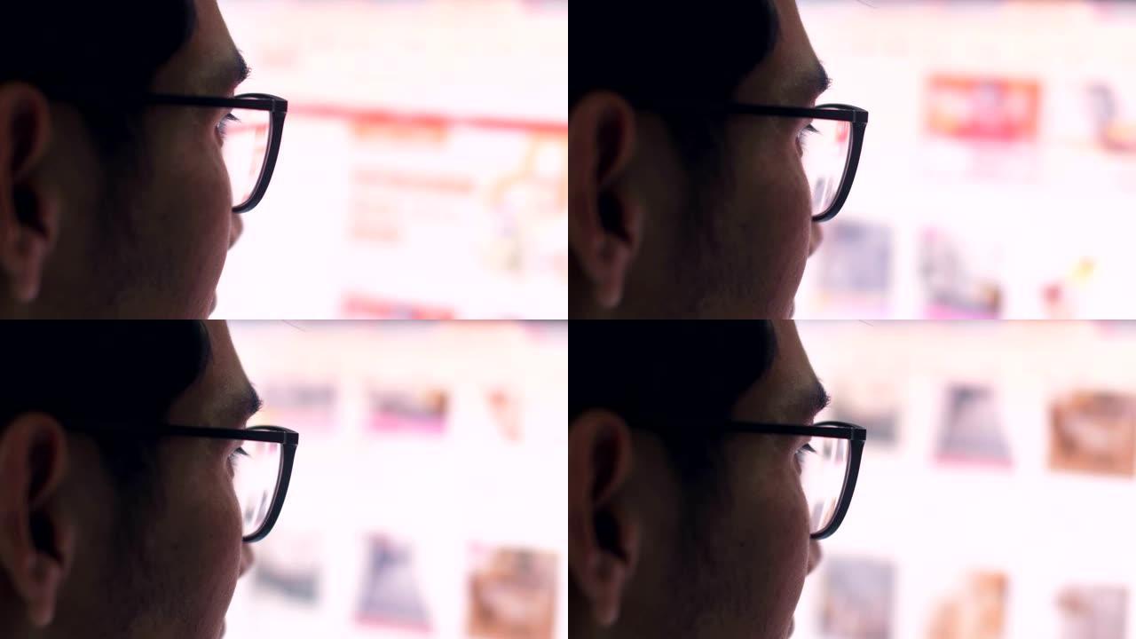 戴眼镜的特写男子看着笔记本电脑屏幕