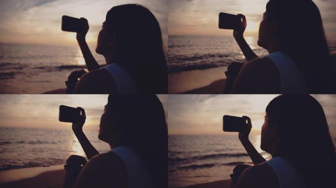 女人在海滩上拍摄日落照片