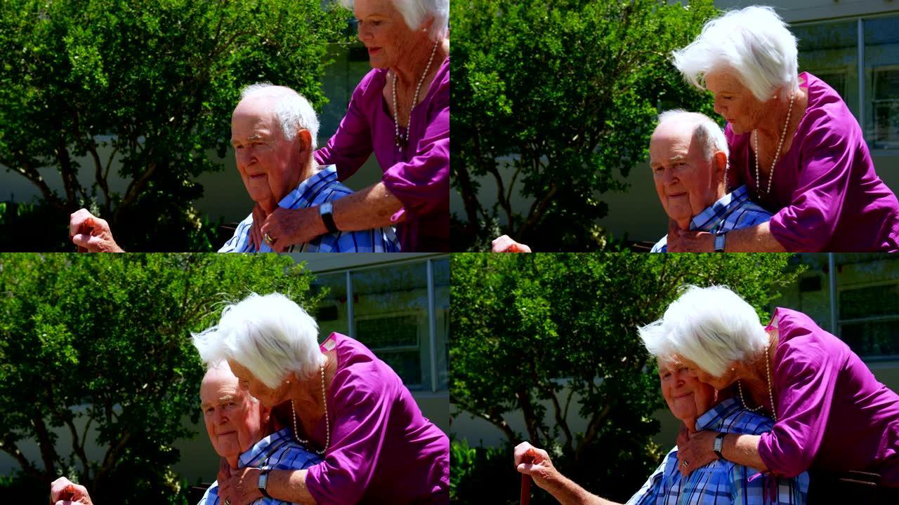 活跃的高加索老年夫妇在养老院4k花园中互相拥抱的侧视图
