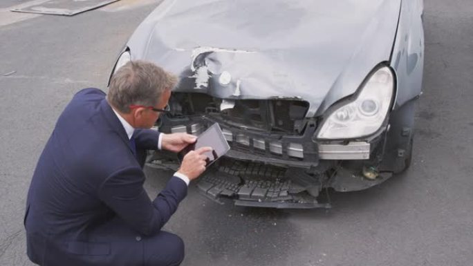 保险损失理算员用数字平板电脑拍摄汽车事故损坏的照片