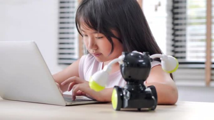 女孩在家中在计算机上进行构建和编程，并将其作为学校科学项目来构建机器人。她对自己的工作非常满意。教育