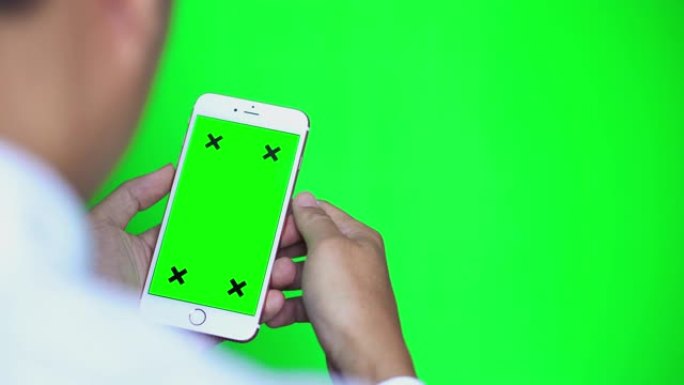 绿色屏幕和绿色背景的智能手机的肩膀拍摄
