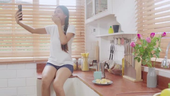 年轻的亚洲青少年妇女在家中vlog，女性使用智能手机在厨房的社交媒体上制作vlog视频。生活方式女人