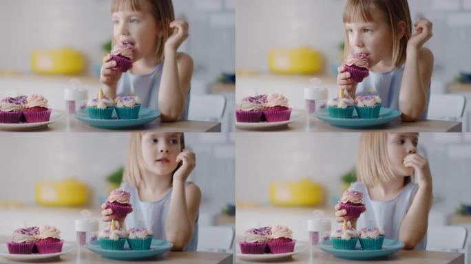 在厨房里: 可爱的小女孩吃奶油蛋糕，糖霜和洒满Funfetti。可爱的饥饿的甜食孩子咬成松饼，含糖糖