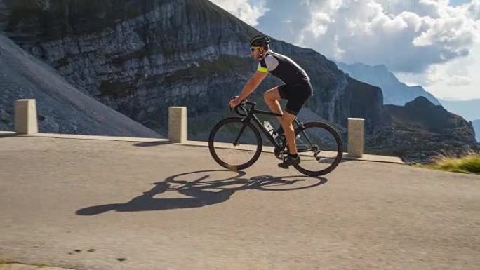 男性公路自行车手在山口上坡踩踏板