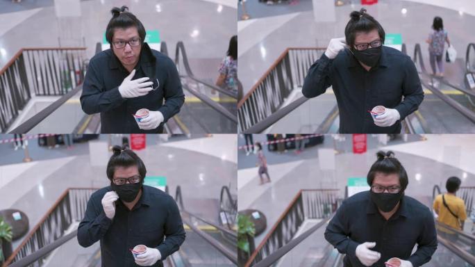 男子站在纸杯上吃冰淇淋，然后在百货公司的自动扶梯上戴口罩