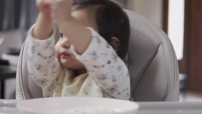 女婴在家里的客厅里吃母亲喂养的食物。