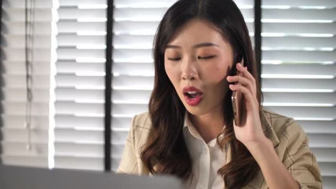 年轻的亚洲妇女在办公室使用电话