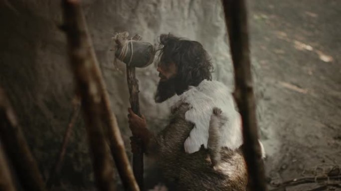 戴着动物皮的原始穴居人拿着石尖矛，站在洞穴入口处，俯瞰史前森林，准备捕猎动物猎物。尼安德特人去丛林打