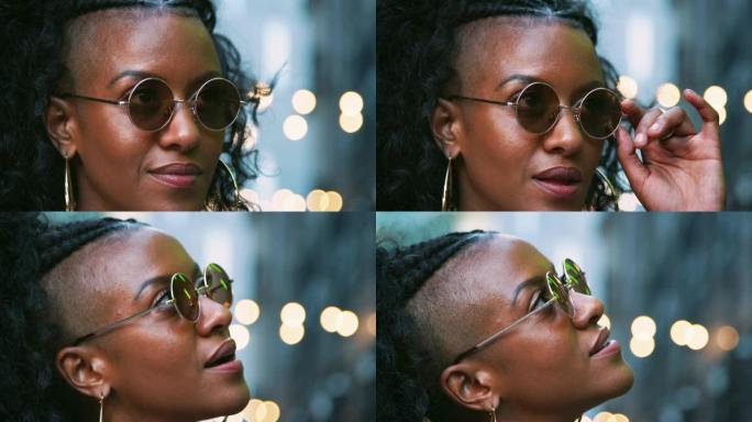 时尚的年轻黑人女性戴着墨镜抬头，头部拍摄，背景为bokeh灯
