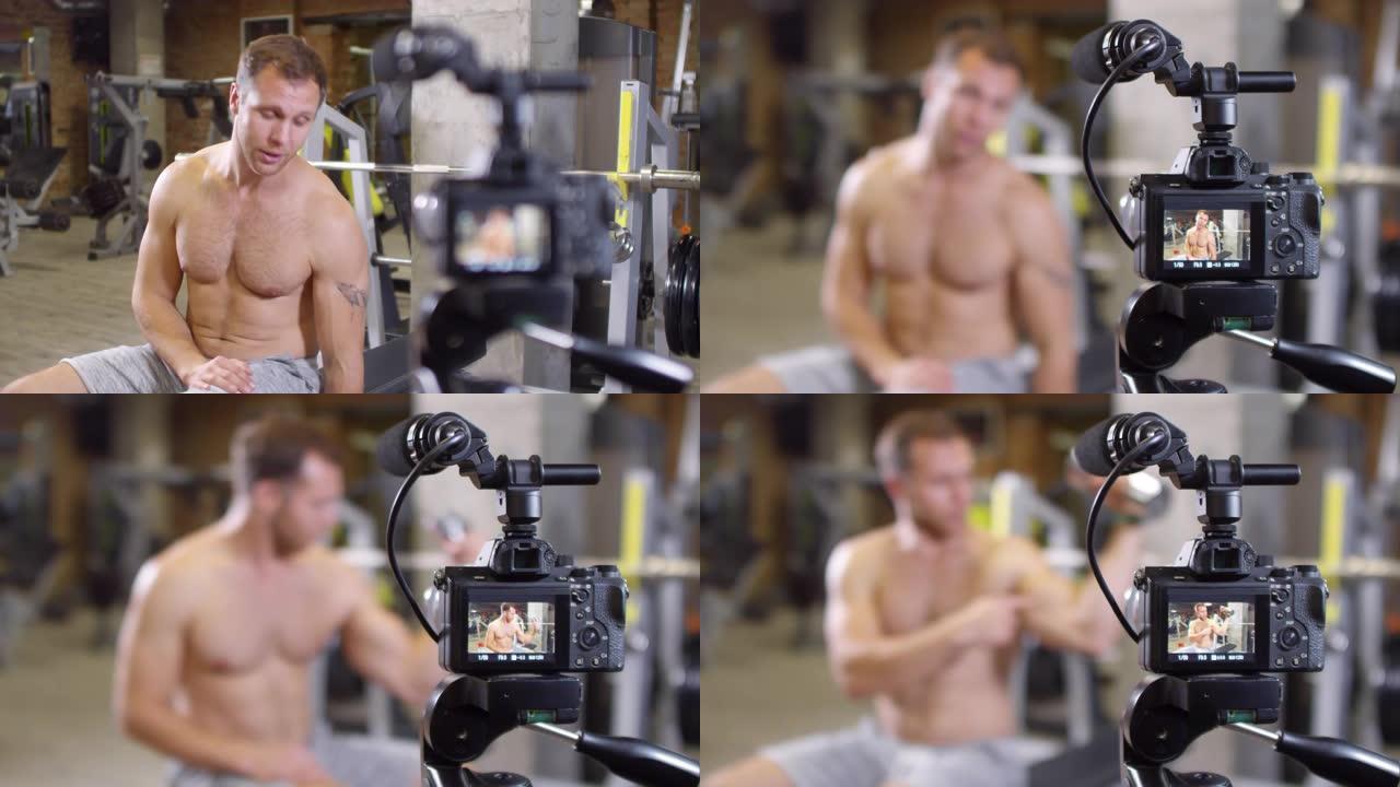 光着膀子的健身教练在相机上展示哑铃锻炼