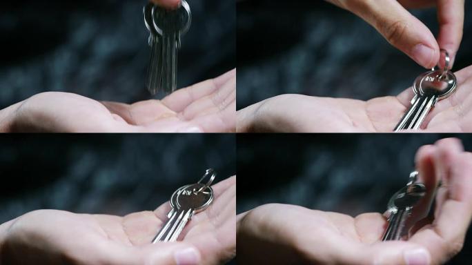 房子的钥匙或另一把锁，把钥匙放在手里，在黑暗的背景上。