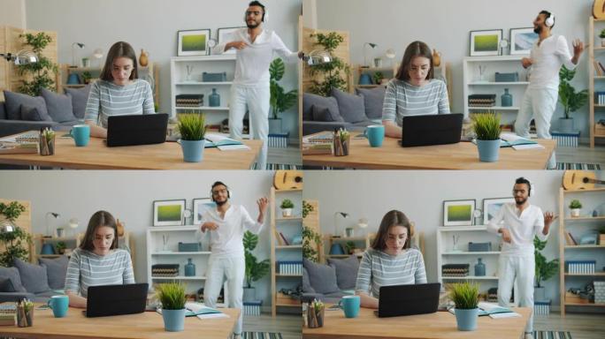 年轻的女士在家里用笔记本电脑工作，而阿拉伯男人在背景中跳舞
