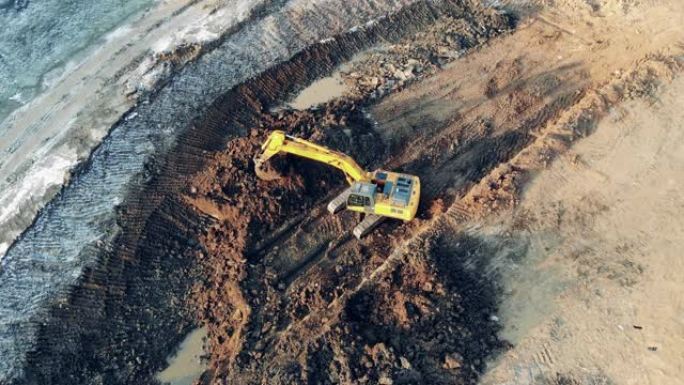 黄色挖掘机在采石场工作时移动泥土。工业建筑工地的重型机械。