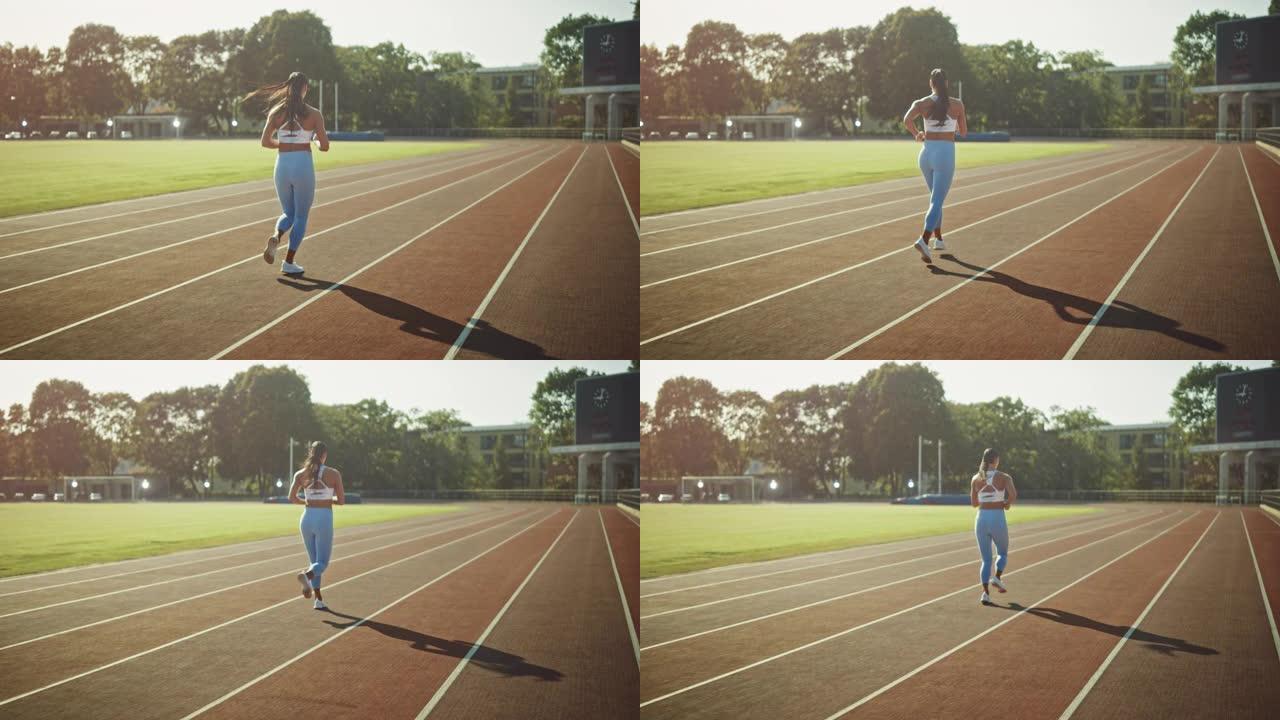 穿着浅蓝色运动上衣和打底裤的美丽健身女孩在体育场慢跑。她在一个温暖的夏日下午跑步。运动员在赛道上进行