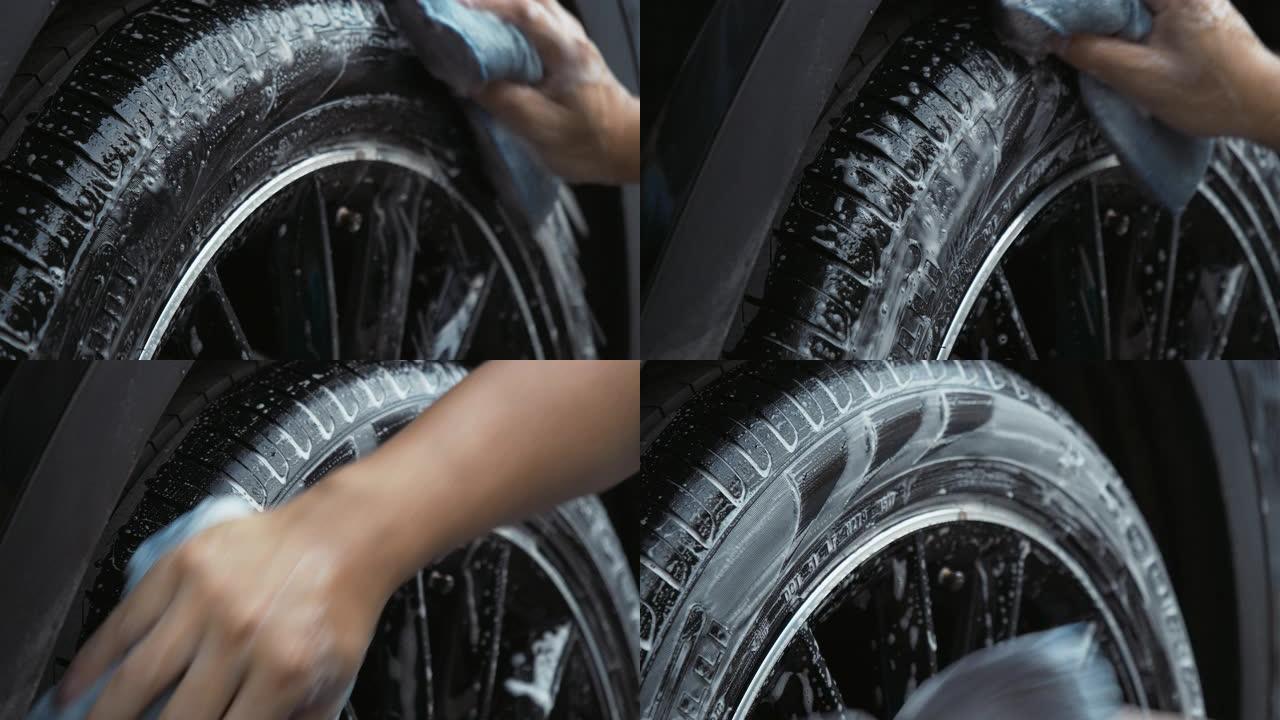 用海绵清洗汽车轮胎的人。