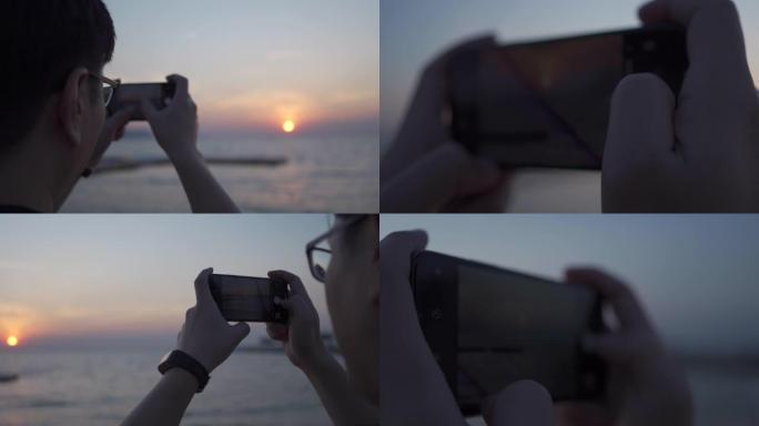 亚洲男子拿手机带手机在海边落日