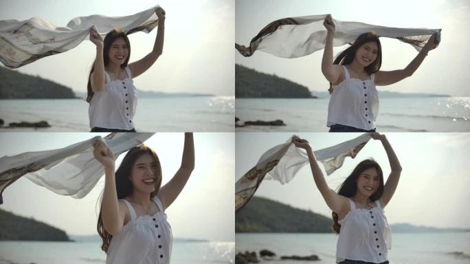 慢动作亚洲女人飘动围巾在海滩上旋转