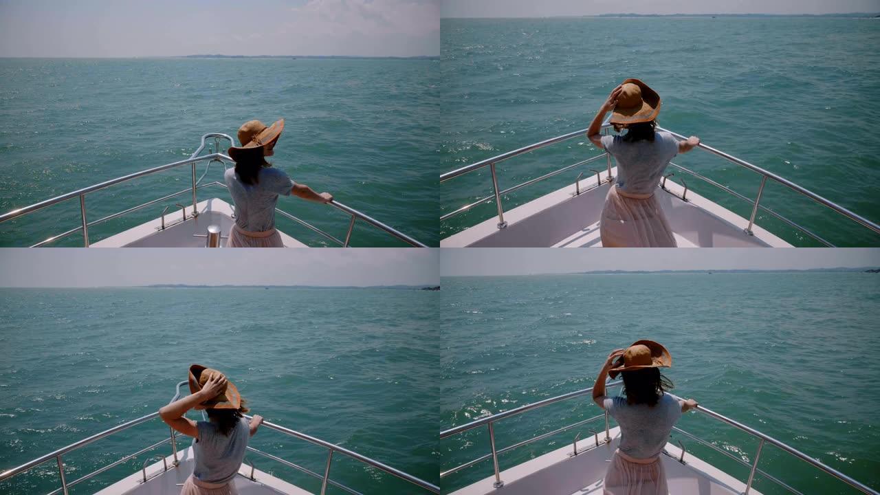 快乐的年轻旅游女人在邮轮游艇上戴着帽子，享受假期中完美的多风阳光明媚的海帆。